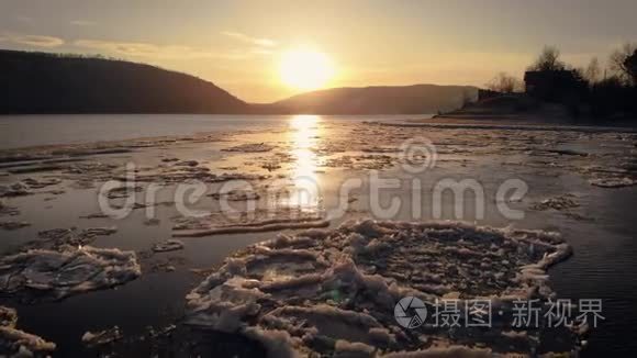 这一个鸟瞰图。 日落于山。 河流或湖泊上覆盖着人，在岸边结冰。 低