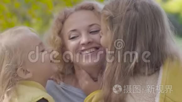 两个漂亮的白种人女孩亲吻母亲脸颊的肖像。 快乐的姐妹们向他们表达他们的爱