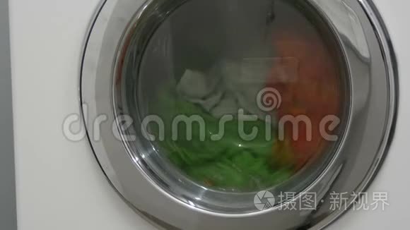 多种颜色的衣服洗衣在洗衣房的白色洗衣机里洗。