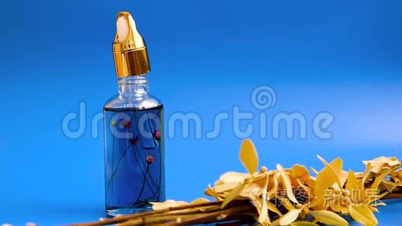 滴头玻璃瓶在蓝色背景上用干花在女性手中