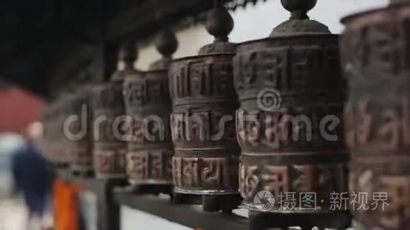 在尼泊尔加德满都的一排轮子上旋转佛教祈祷轮的近景。 神庙。