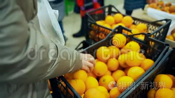 超市里的女人选择橘子。 商店里的一盒橘子。