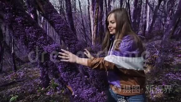 紫罗兰童话森林.. 美丽快乐的女孩在阳光明媚的日子里，抚摸着一棵树干，树干上长满了厚厚的紫色苔藓