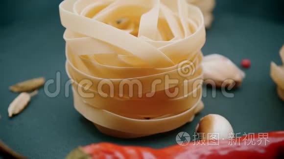 4K视频。 意大利面：用香料在灰色背景上筑巢的fettuccine：辣椒，茴香种子和辣椒.. a.轮调