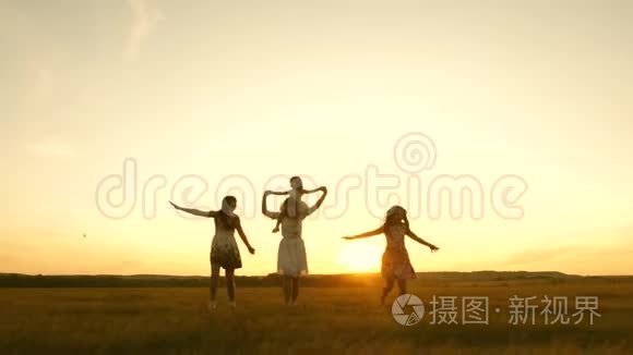 快乐的童年概念。 幸福的年轻家庭带着一个孩子在日落时分的飞行中跑过田野。 母亲和