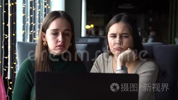两个年轻的女商人坐在一张桌子旁，手提电脑的咖啡馆里