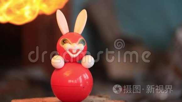 儿童旧塑料玩具兔子从炽热的火焰中融化。 慢速视频