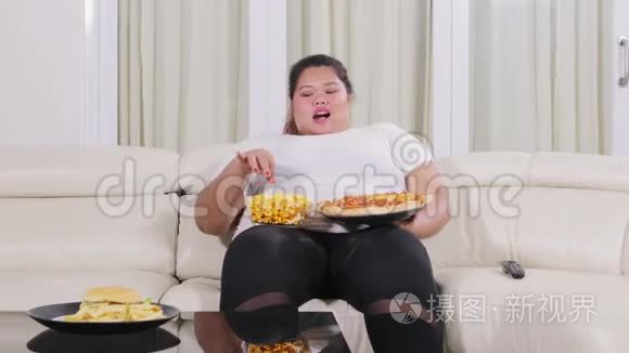 超重妇女在沙发上吃垃圾食品视频