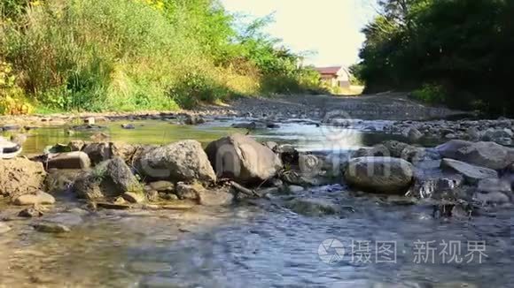 一个女人在右边的岩石上过河。 背景上的森林。 双腿合拢。 积极的概念