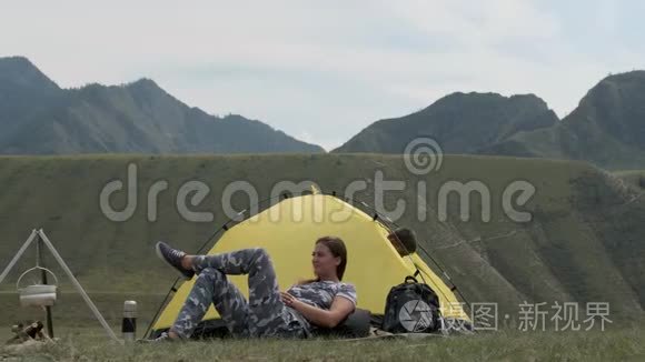 妈妈和儿子正在帐篷前的一个营地休息。 男孩睡觉后离开帐篷，拉着他的手