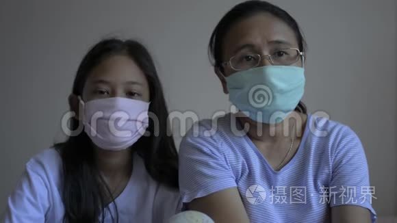 母亲和女儿戴着防护面罩，以保护自己免受电晕病毒的影响，并呆在家里。