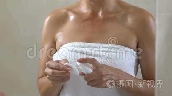 女人在浴室淋浴后在脸上涂润肤露，护肤