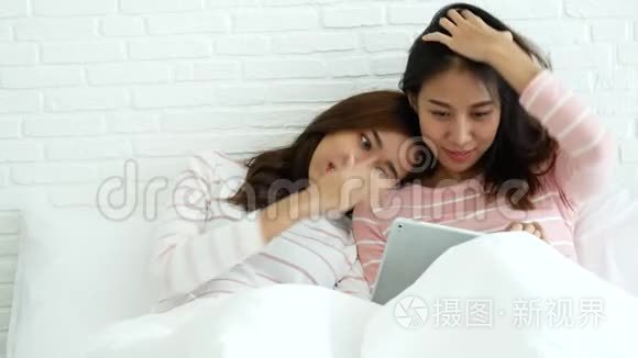 两个漂亮的好朋友永远的女朋友在床上聊天，拥抱和欢笑，在舒适的家庭关系中坠入爱河。 女同性恋夫妇