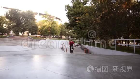 男子骑着BMX自行车在户外滑冰公园从坡道上跳到空中。 年轻人一个人在空车里