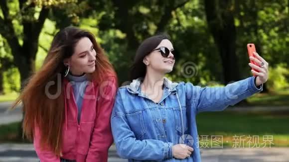 两个快乐的女孩朋友在城市公园的手机上自拍。