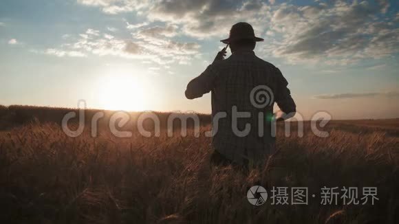 年轻的农民在田里打电话。 智慧农业技术.. 男子手持平板电脑在农场使用