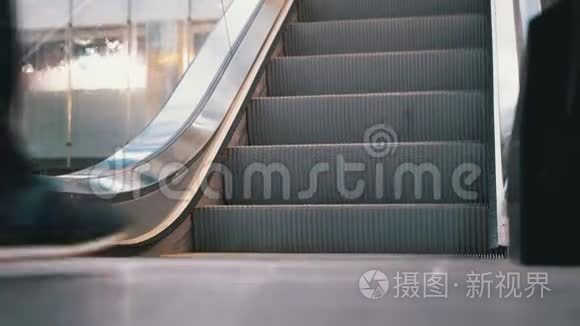 人们的腿在商场的自动扶梯电梯上移动。 购物中心扶梯上的购物者脚