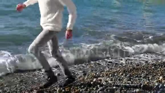年轻人在岩石和海水上奔跑，在鹅卵石海滩上慢动作