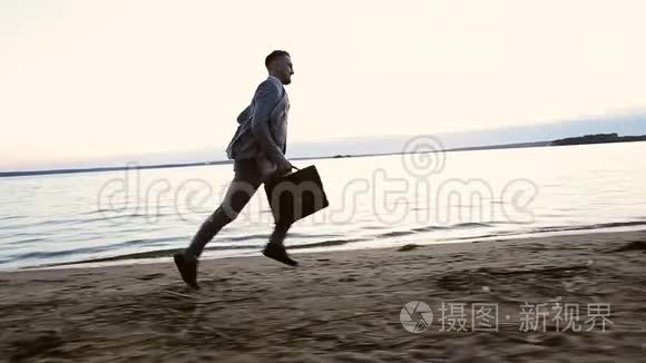 快乐的商人手里拿着公文包，日落时分在海滩上奔跑。