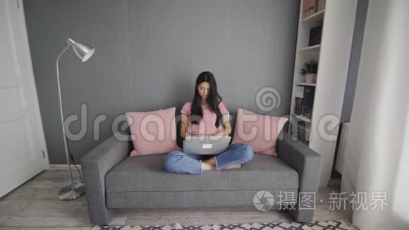 一个漂亮的女人在沙发上用电脑工作