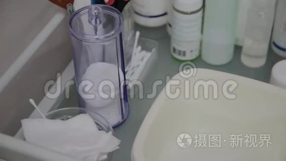 在透明玻璃杯中特写棉垫。 一个女人`手拿一个棉垫。