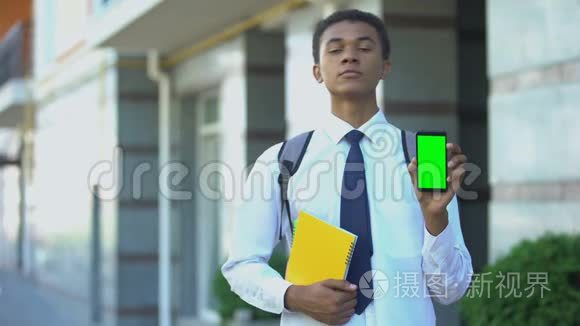 自信的黑人男学生，书上显示绿色屏幕智能手机，应用程序