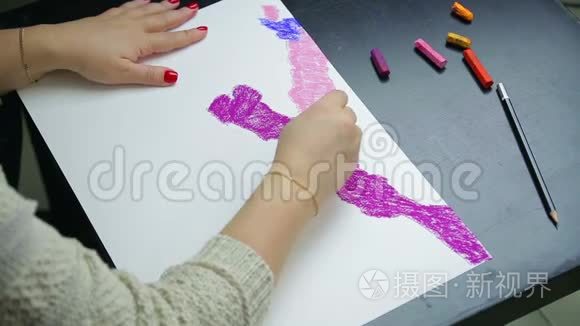 日落时分，女人的手在白纸上画着紫色的彩纸