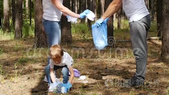 家庭积极分子在树林里收集垃圾。 孩子把垃圾放在一个可生物降解的袋子里。 关怀的概念