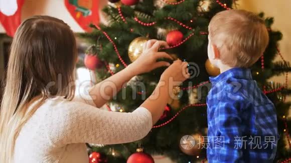 小男孩和妈妈在客厅装饰圣诞树的4K镜头。 冬季家庭装饰屋
