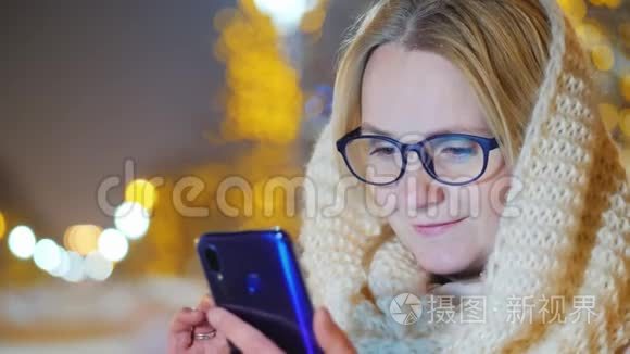 一位年轻女子晚上在雪地街道上使用智能手机的肖像