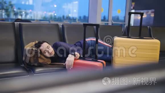 一个女人睡在机场候机楼的长凳上。 在飞机上等待长时间的转机