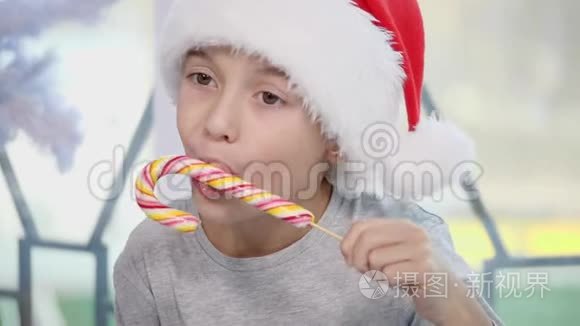 漂亮的小男孩正在品尝一种糖果，在圣诞节的早晨，看起来很好奇。