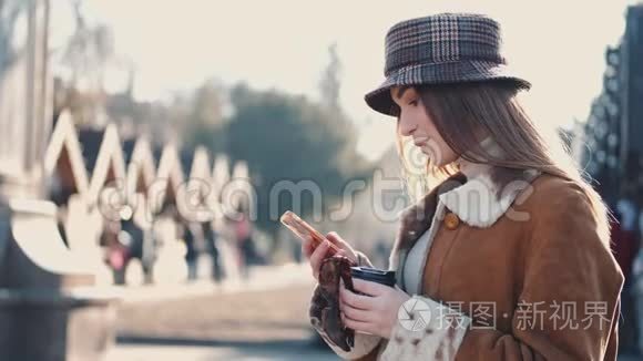 一个戴着帽子的漂亮黑发女人正在城市街道上喝一杯外卖咖啡