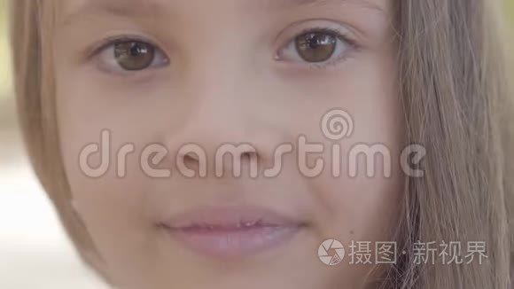 一个小可爱的棕色眼睛女孩的特写，黑发女孩对着镜头微笑。 可爱的白种人儿童