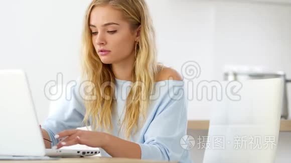 有魅力的年轻学生女孩正在家里学习，使用笔记本电脑打字和阅读反馈信息。 教育和生活方式概念