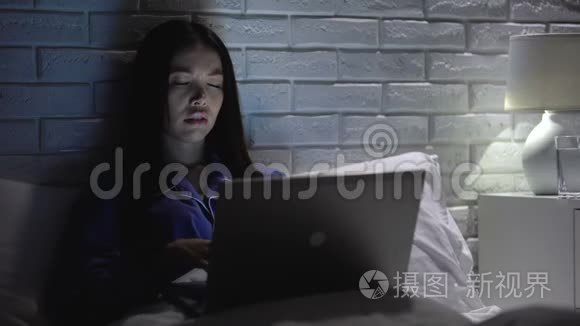 疲劳的女人在家工作到很晚，服用头痛药，刺激疲劳