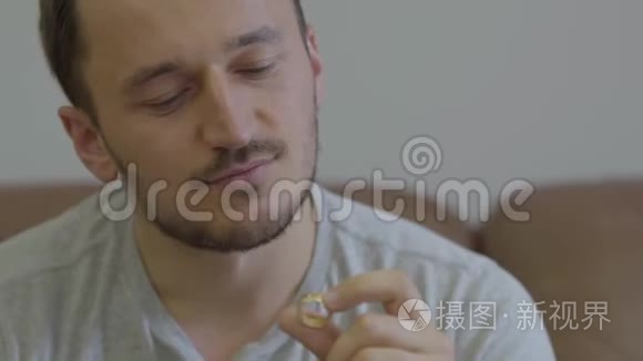 幸福的男人捧着金色结婚戒指的画像微笑着坐在家里。 他要提出一个建议