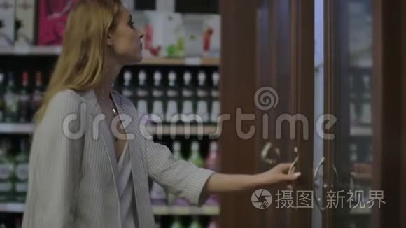 女士在超市选择葡萄酒，顾客在商店的货架上选择产品。 卖酒精。 读一读