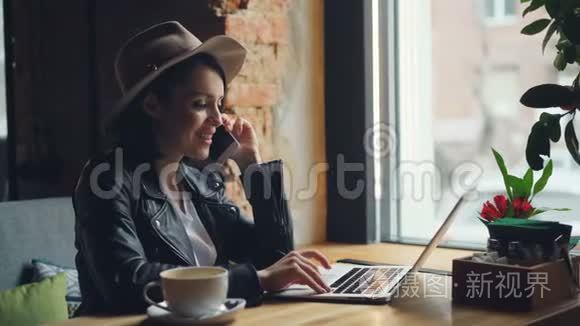 快乐的年轻女子在咖啡馆里用手提电脑打电话
