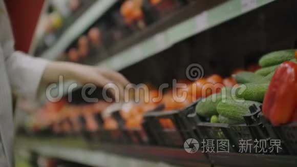 在超市里挑选黄瓜和蔬菜的女人。 购物选择购买水果，蔬菜。 少女