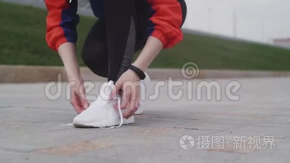 年轻的运动女性系鞋带和大步跑