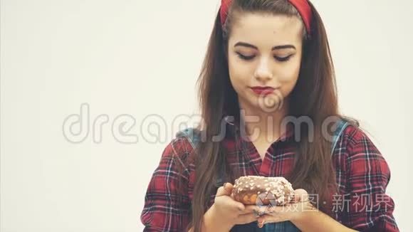 可爱的年轻女性建议你品尝大巧克力甜甜圈，通过她的脸表情显示它是非常美味的。