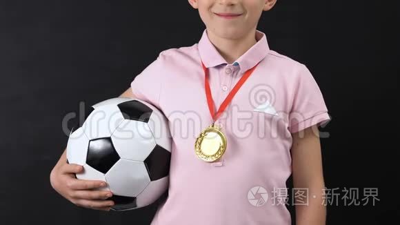 快乐的小男孩，脖子上戴着金牌，手持足球，比赛