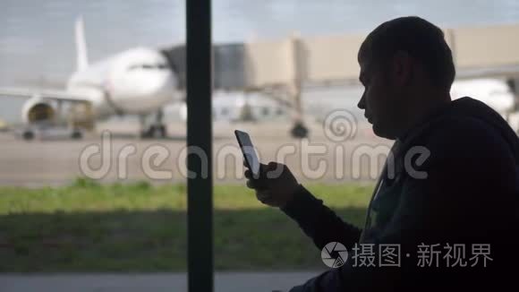 商人在机场用电话。 男人旅行者的剪影。