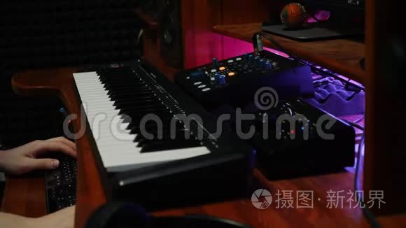 音乐工程师在家庭录音室为音乐专辑创作新的热门歌曲。男性手指在钢琴midi键盘上，近距离。手