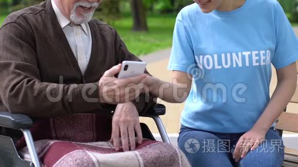 女志愿者教坐轮椅的老人如何使用手机