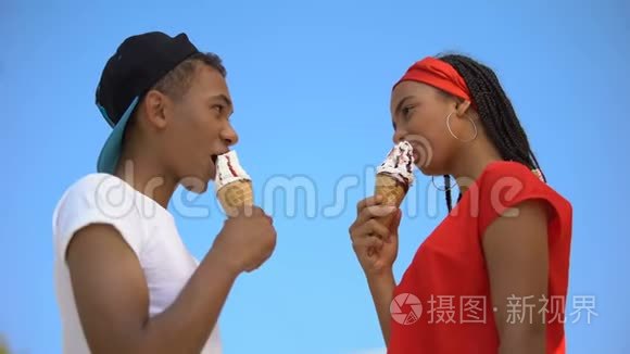两个混血的青少年吃着甜的冰淇淋蛋筒，有胃口，有底景