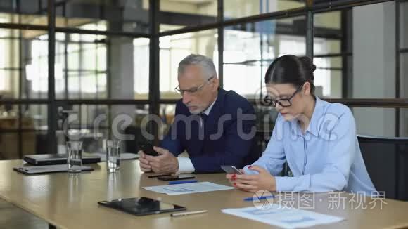 两位办公室经理在等待业务客户的智能手机上输入电子邮件