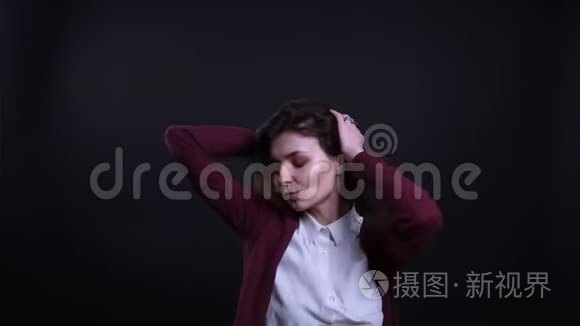 年轻的黑发女商人在黑色背景下积极快乐地跳舞的肖像。