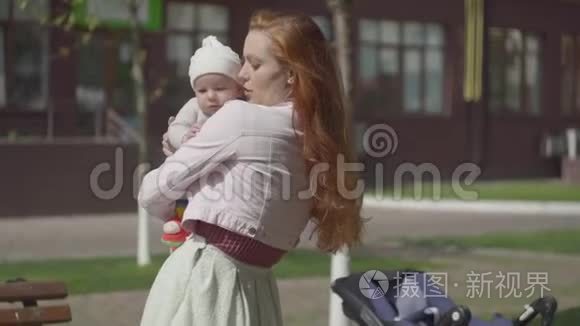 可爱的女人抱着孩子在院子里特写的肖像。 这位女士享受着阳光明媚的一天